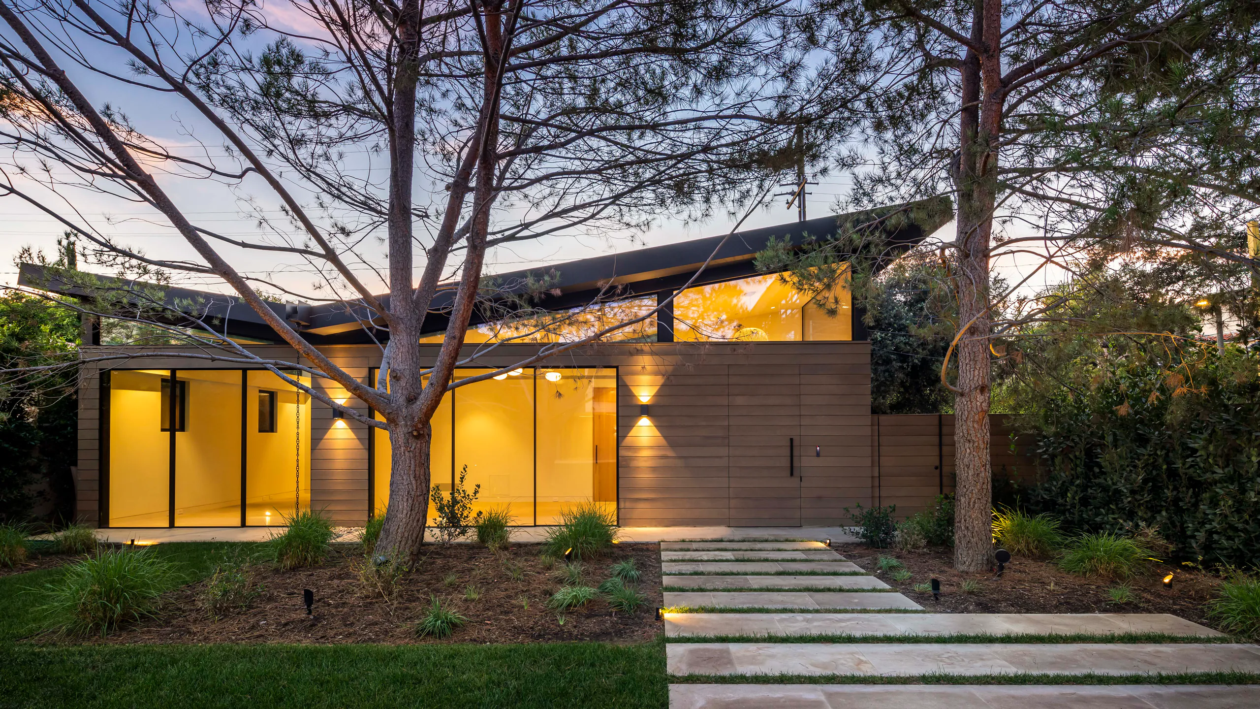 Woodland residence illuminated behind mature tropical planting