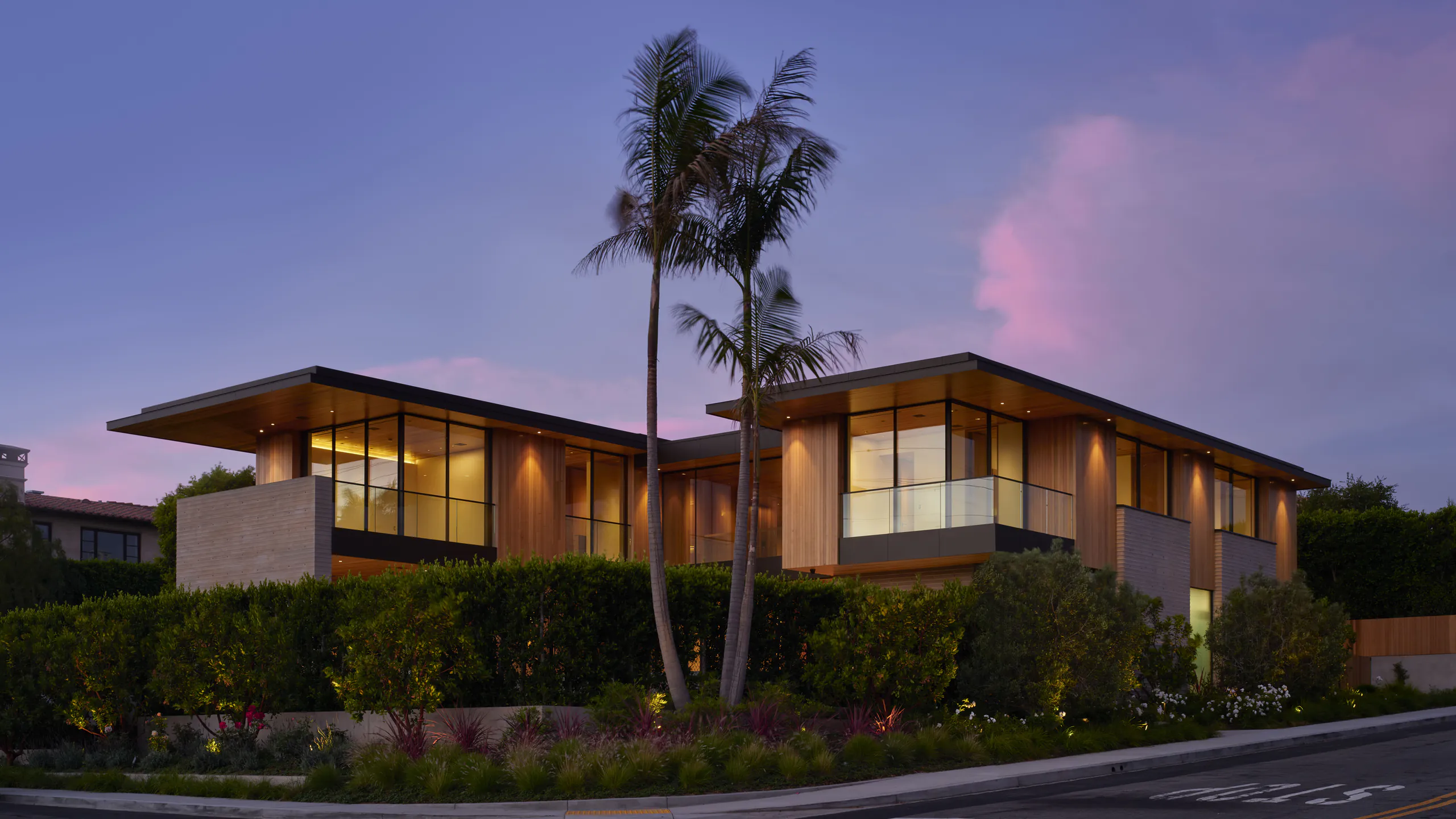 Palm-framed contemporary residence illuminated beneath a warm evening sky